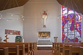Raum von Mitte, oben 2 Radleuchter, hinten 4 Mosaike, Kanzel, Altar mit Christkönig, Taufe und Buntglasfenster 'Jonas im Walmaul'